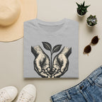 T-shirt — « Entre de bonnes mains » — Illustration graphique de mains tenant une jeune pousse